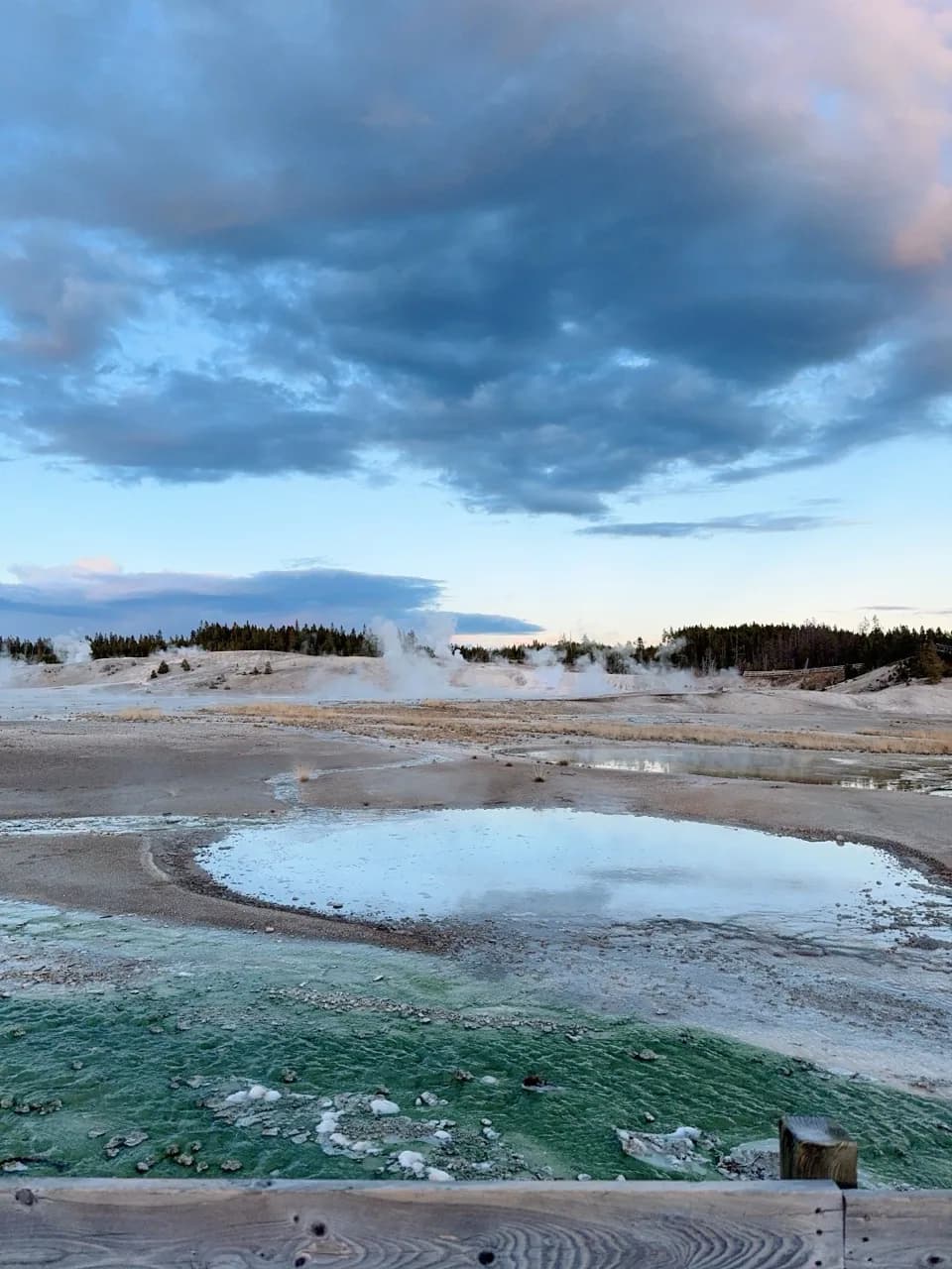 Geothermal pools and steam viewed from a boardwalk overlook.