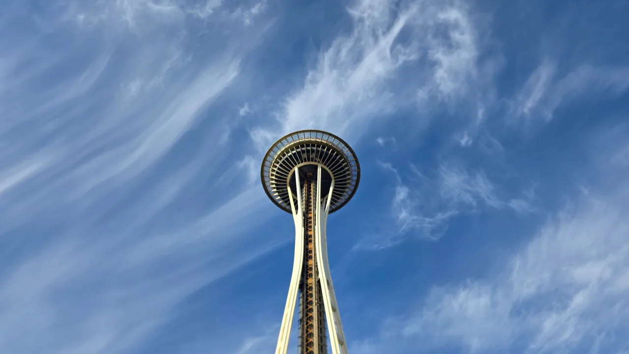 Space Needle rising into a sky streaked with high clouds.