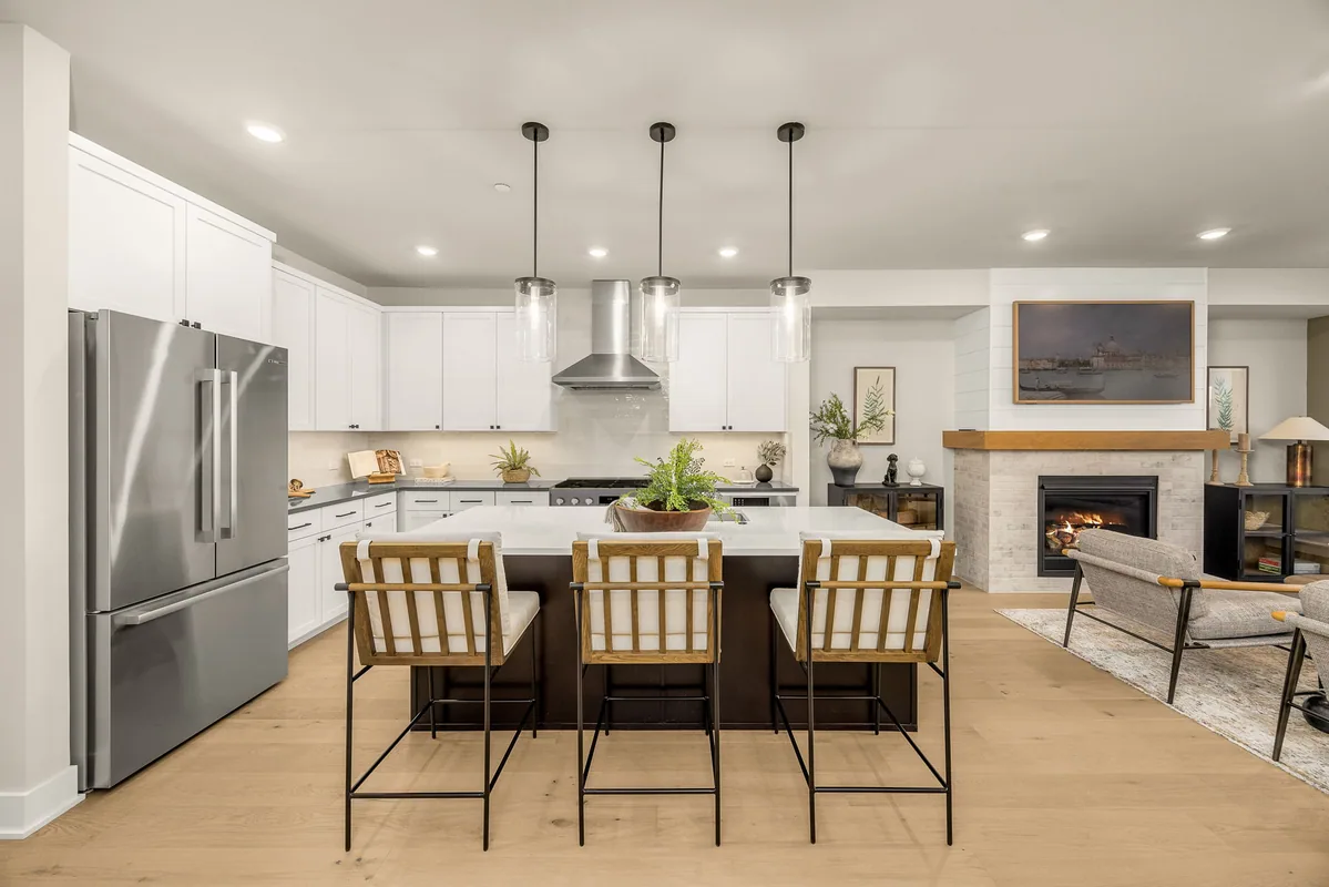 Homesite 4 kitchen with a large quartz island, stainless appliances, and fireplace beyond.
